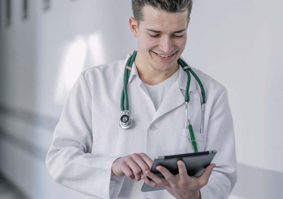 Profissional de saúde utilizando tablet para monitorar dados de pacientes em ambiente digital.